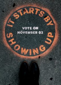 Graffiti that reads, "It Starts by Showing Up. Vote on November 3."