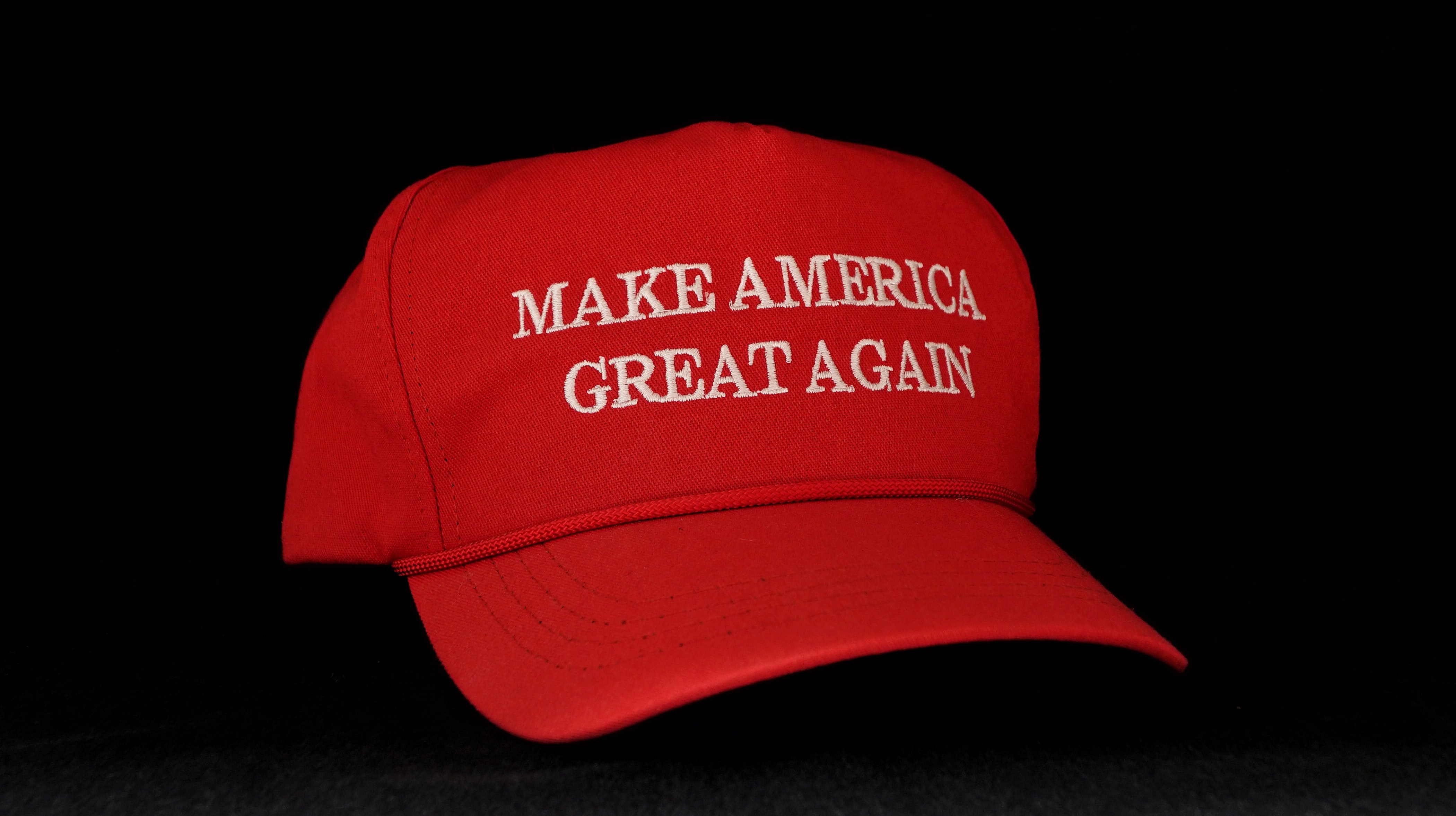 The iconic red "Make America Great Again" hat against a dark background.