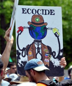 A protester holds up a sign that says "Ecocide."