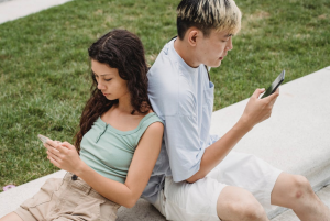 Couple looking at their phones; image by Samson Katt, via Pexels.com.