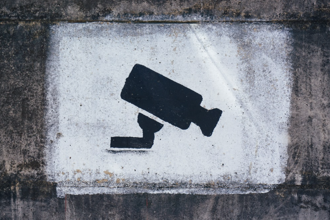 Painting of surveillance camera on wall; image by Tobias Tullius, via Unsplash.com.