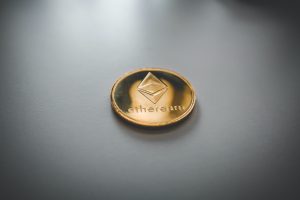 Physical Ethereum (ETH) coin on white surface; image by Nick Chong, via Unsplash.com.