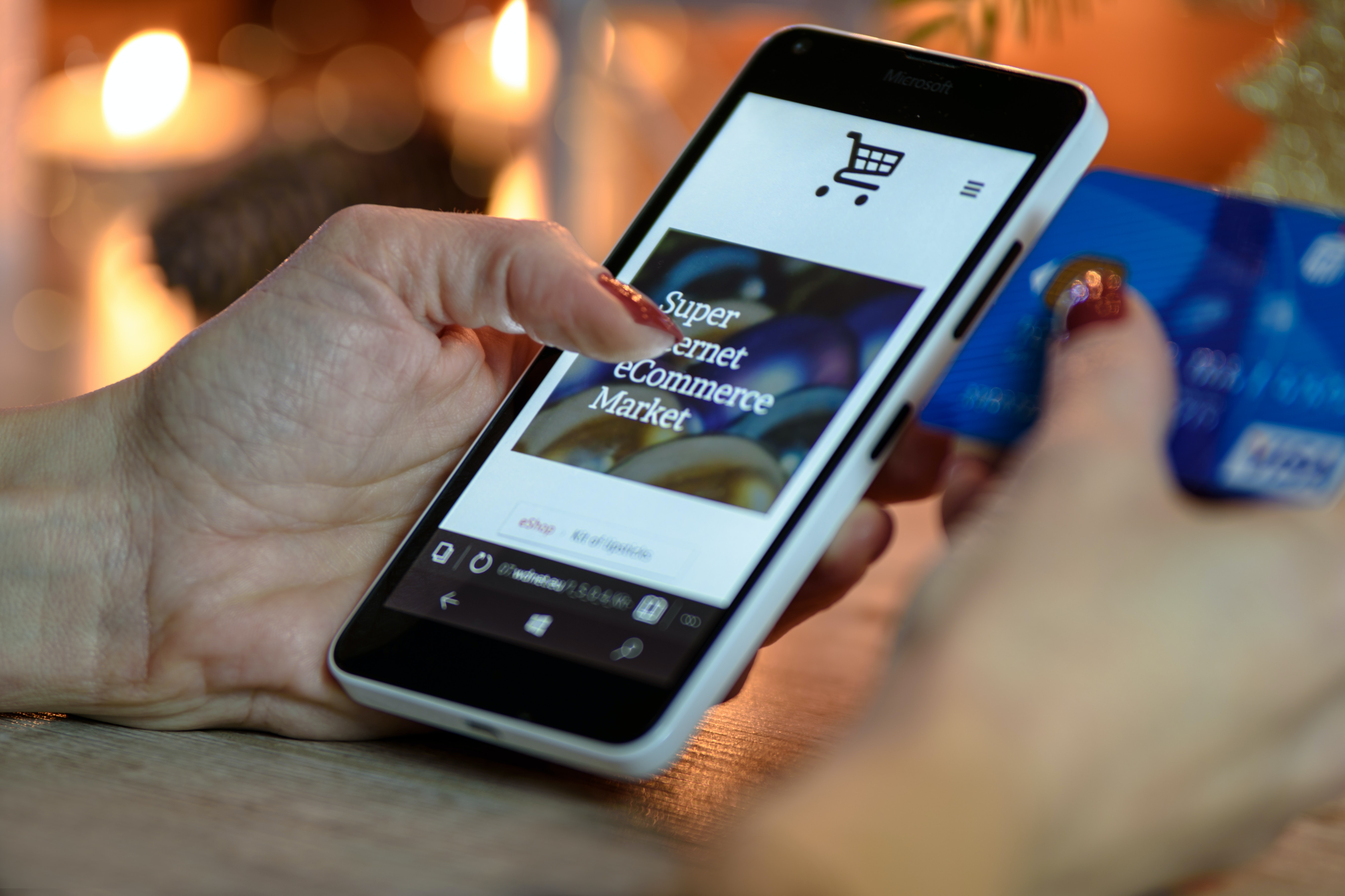 Woman holding smartphone and credit card; image by PhotoMIX Company, via Pexels.com.