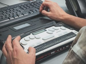 Blind man using a Braille screen reader; image by Sigmund, via Unsplash.com.