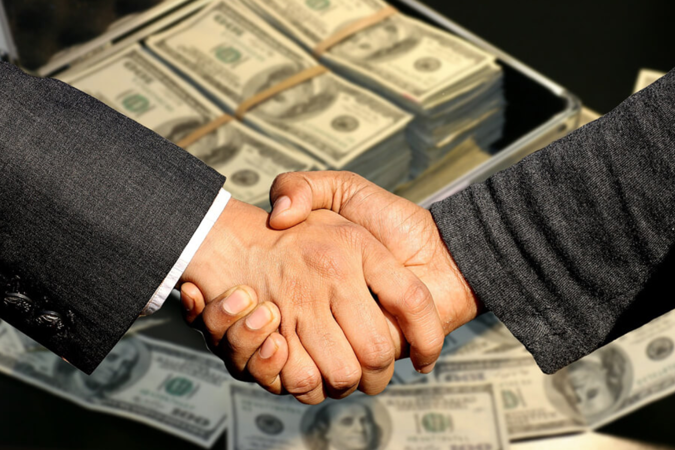 Two men shaking hands over stacks of money; image by Capri23Auto, via Pixabay.com.