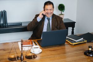 Lawyer at desk talking on smartphone; image by Sora Shimazaki, via Pexels.com.