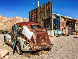 An old car rusting away beside an abandoned business in a remote Nevada ghost town.