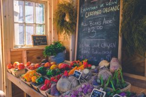 Small boxes of farm vegetables sit on a table for sale.