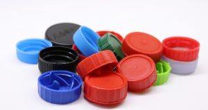 A small collection of differently shaped and colored plastic bottlecaps.