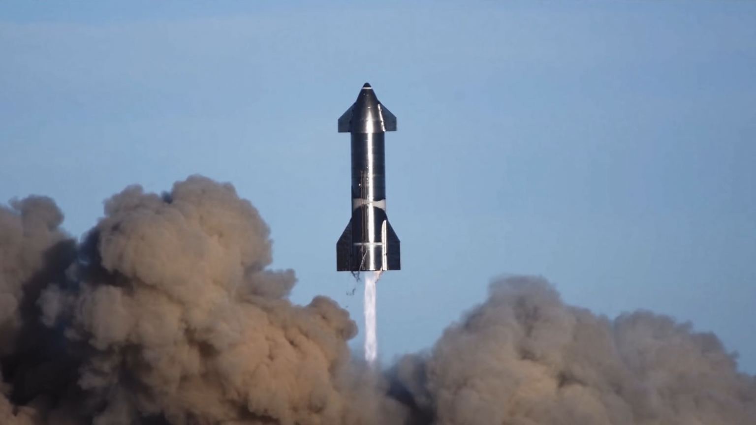 A dark-colored rocket lifts off, with dark, billowing clouds below.