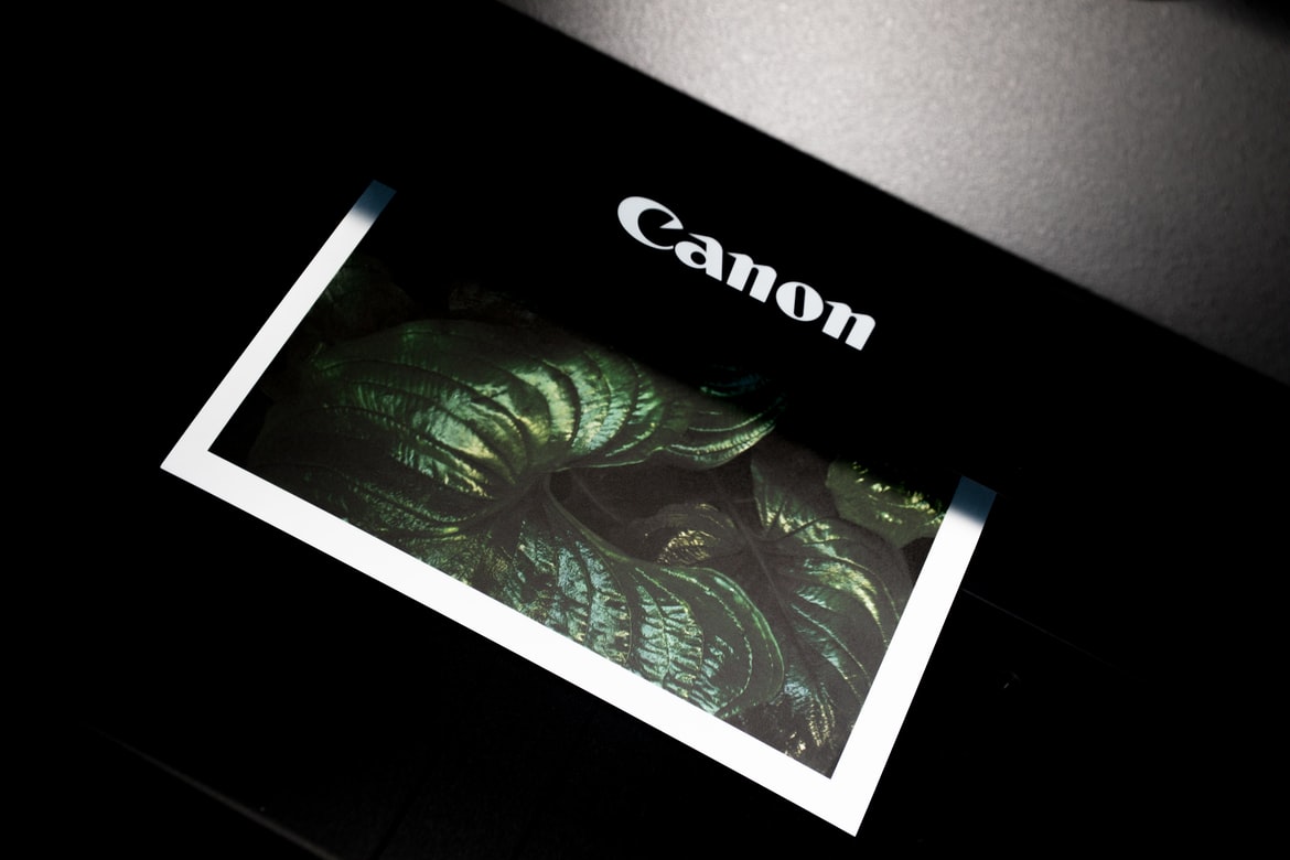 A color print emerging from a black Canon device.