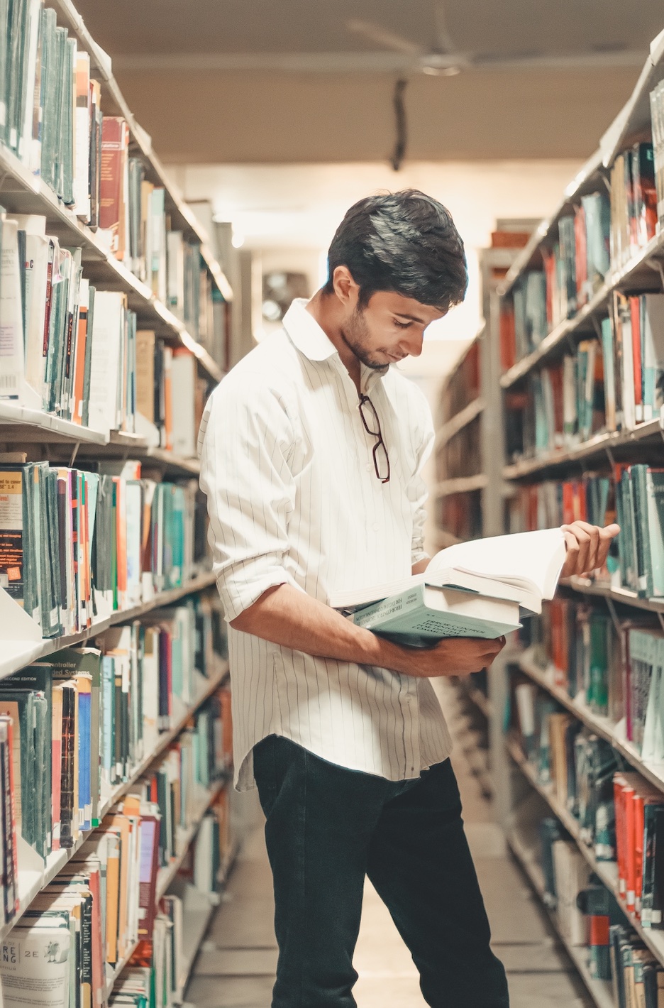 College student at library; image by Dollar Gill, via Unsplash.com.