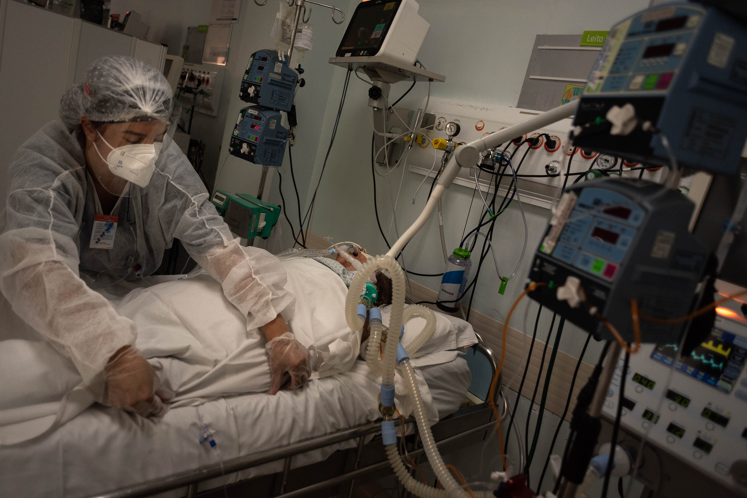 A medic in PPE providing care for a COVID patient in a hospital setting.