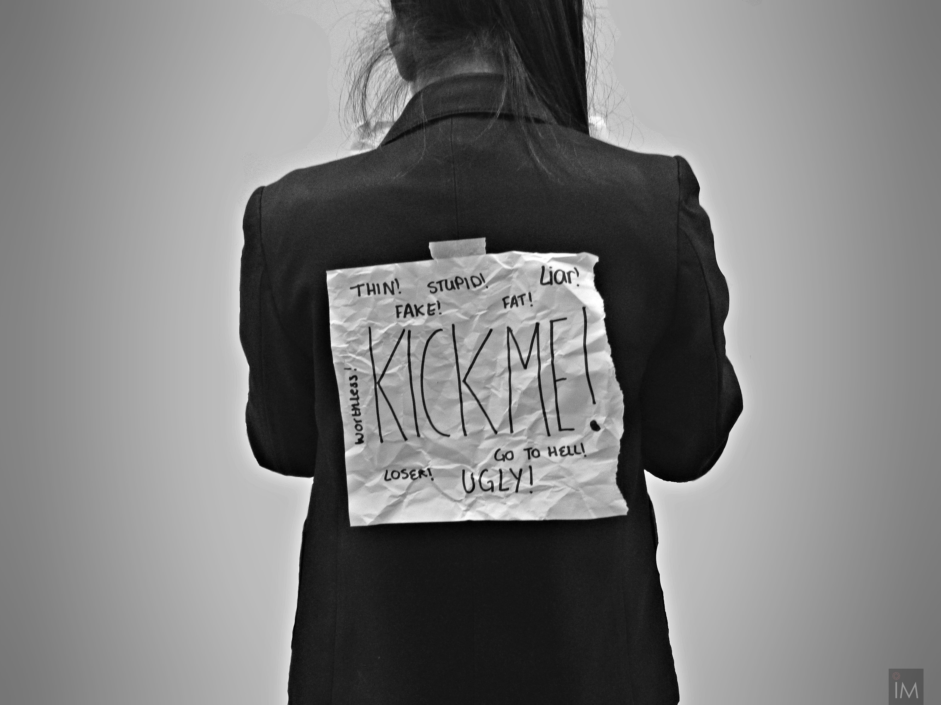 Woman with kick me sign on back; image by Ilayza Macayan, via Unsplash.com.
