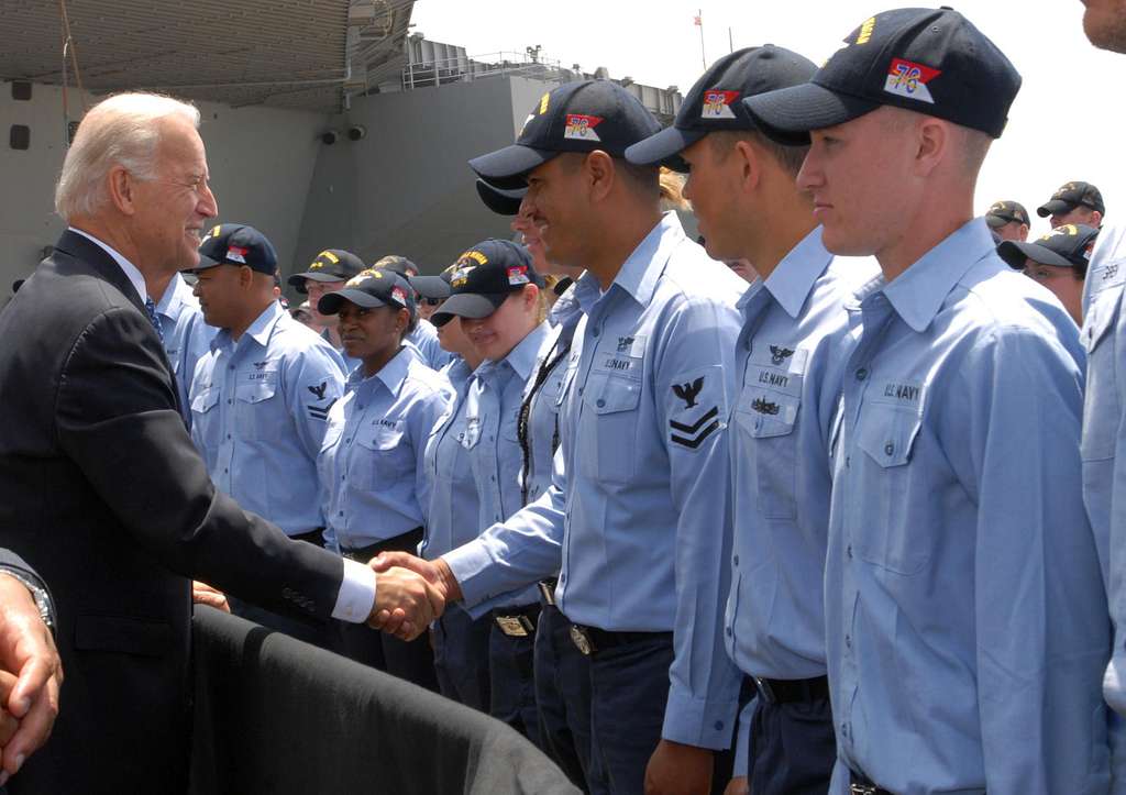 Biden shaking hands with a row of Navy sailors.