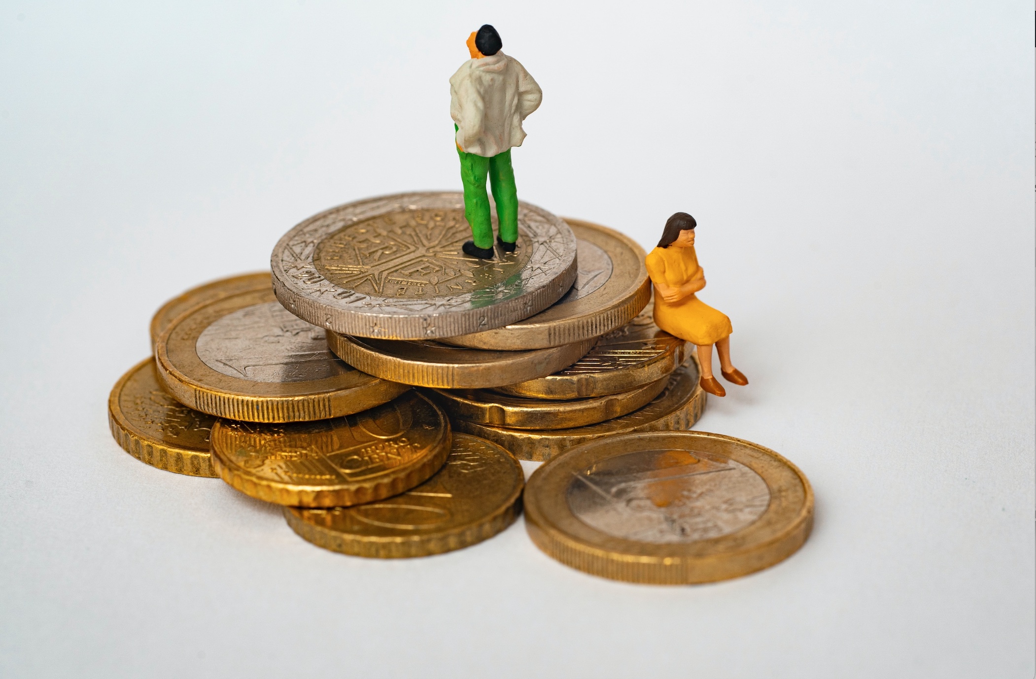 Figures posed on a stack of coins; image by Mathieu Stern, via Unsplash.com.