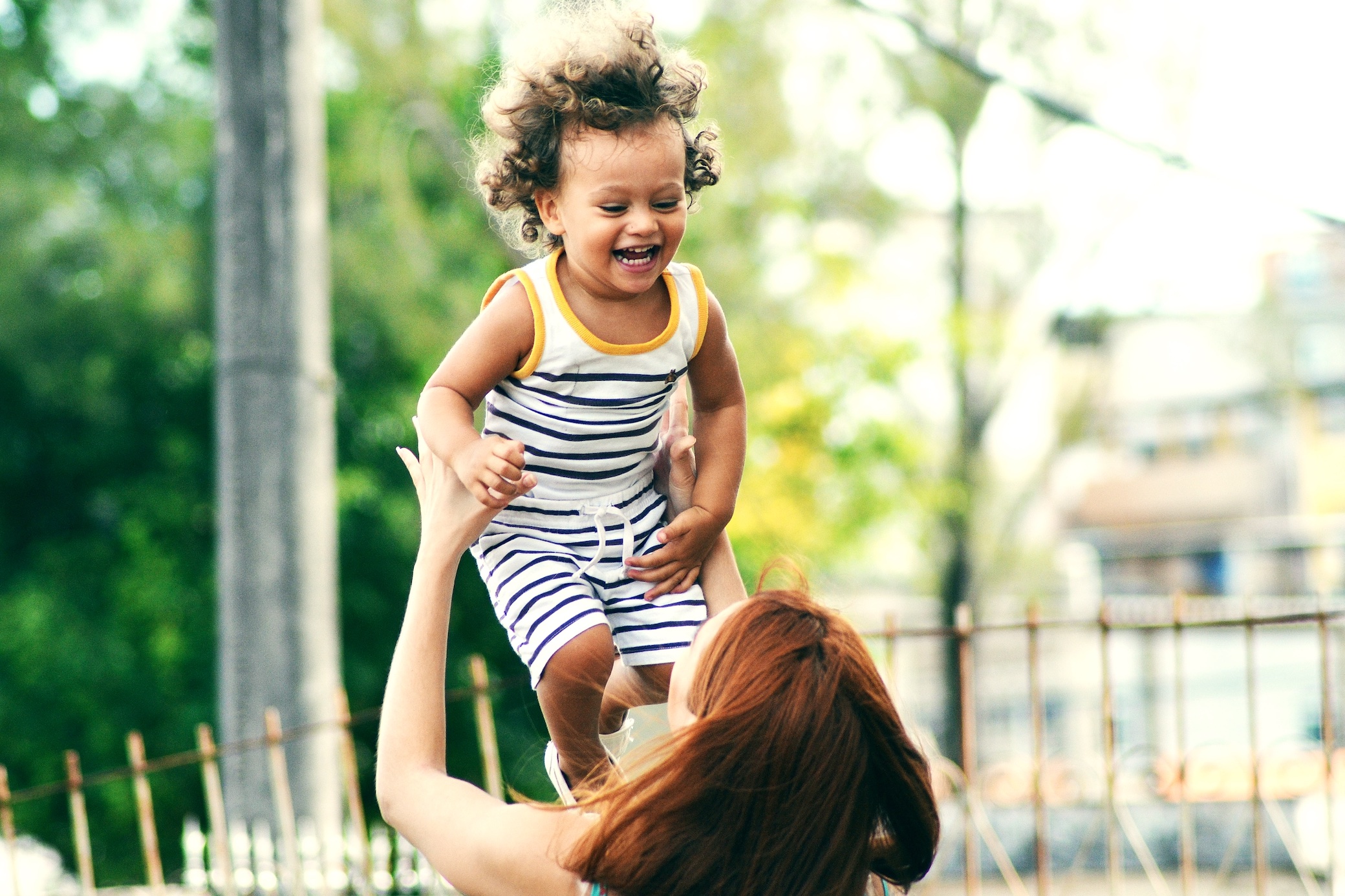 Woman tossing happy child in the air; image by Thiago Cerqueira, via Unsplash.com.