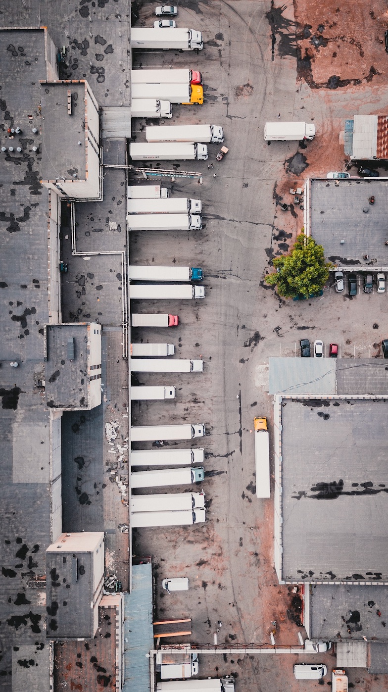 Aerial view of loading dock full of trucks; image by Ivan Bandura, via Unsplash.com.
