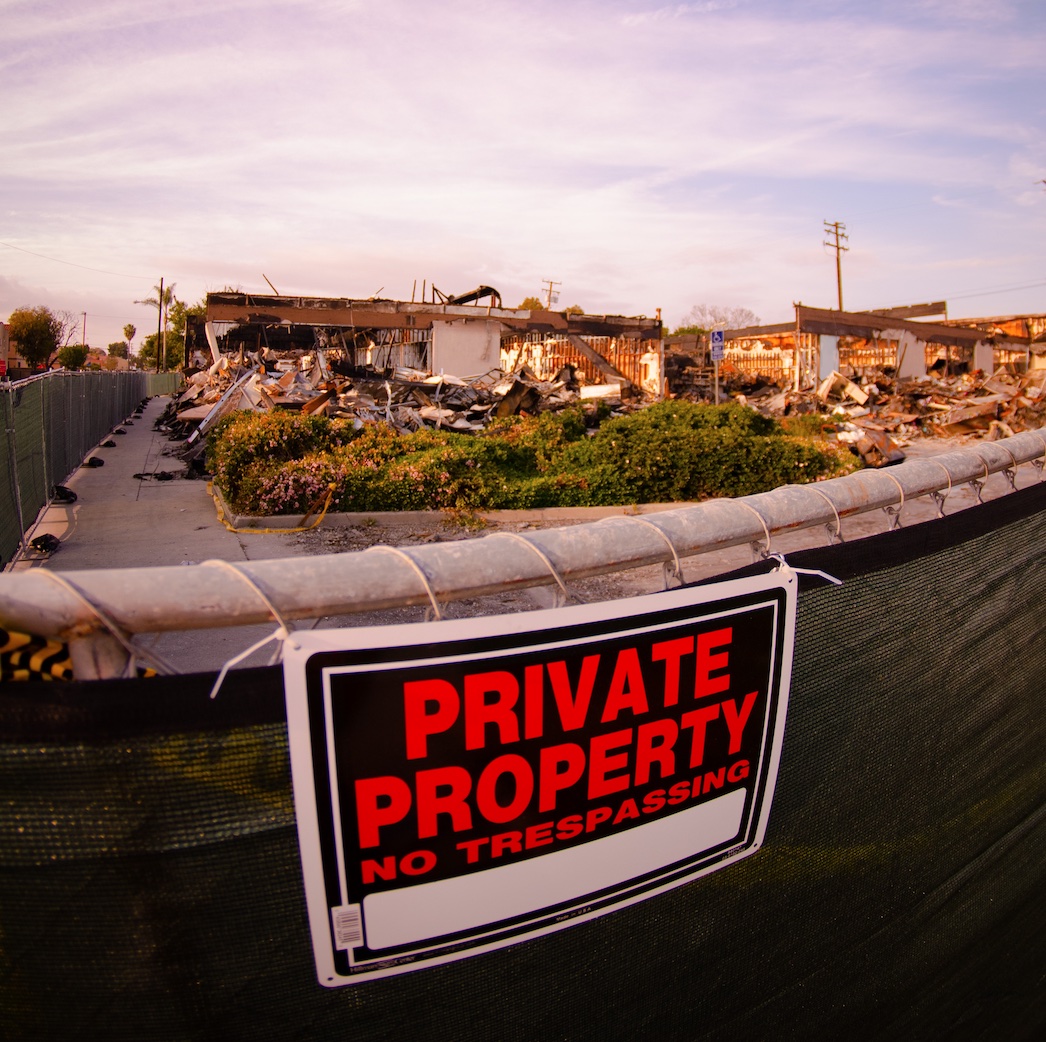 Badly damaged house behind fence with Private Property, No Trespassing sign; image by Kiko Camaclang, via Unsplash.com