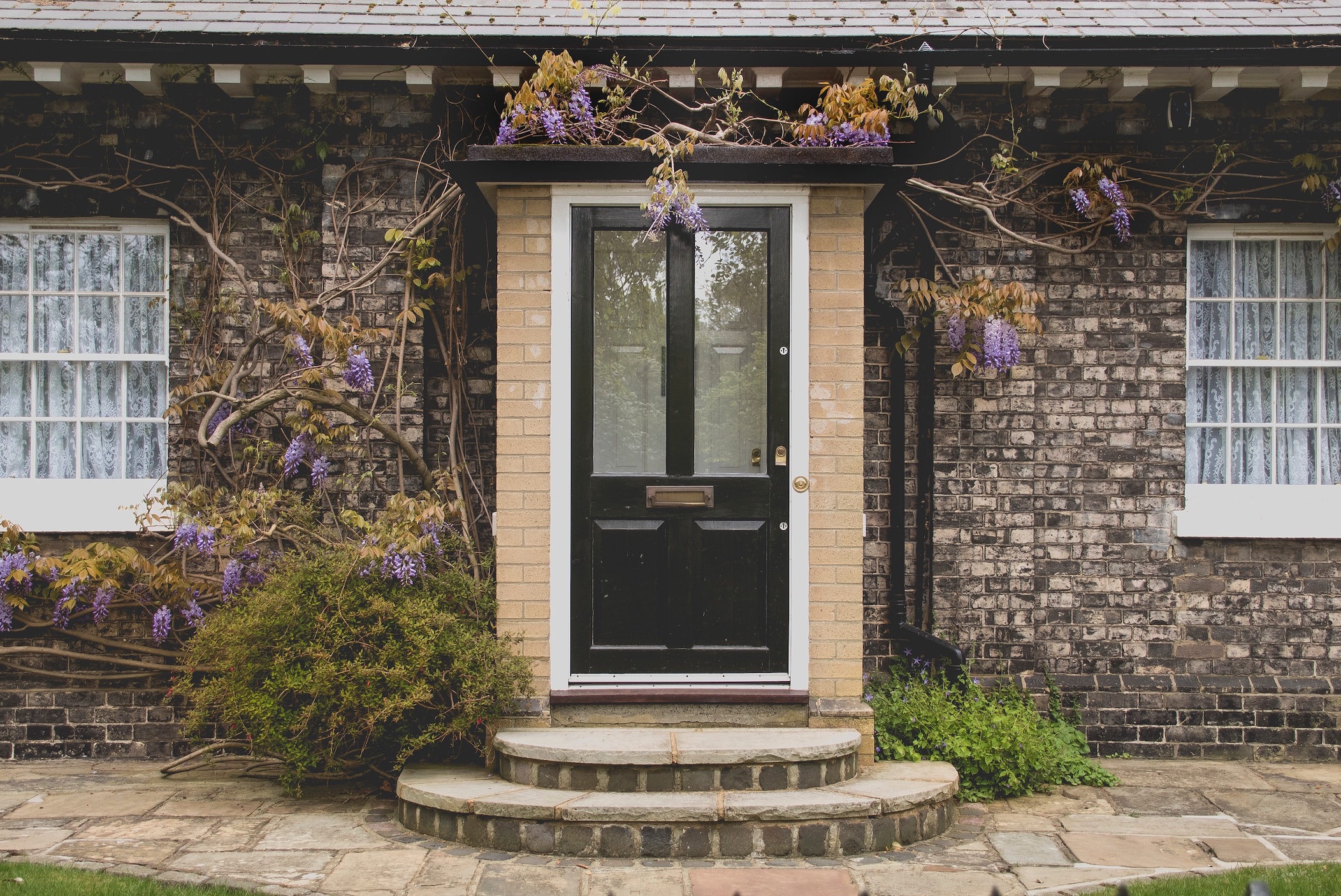 Front door of brick house, with flowers; image by Peter Boccia, via Unsplash.com.