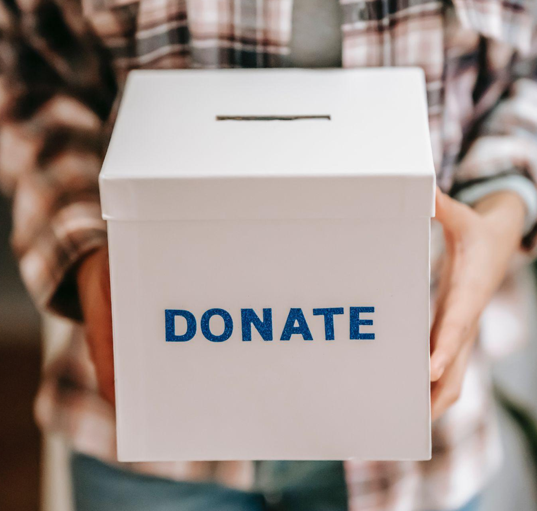 Person holding donation box; image by Liza Summer, via Pexels.com.