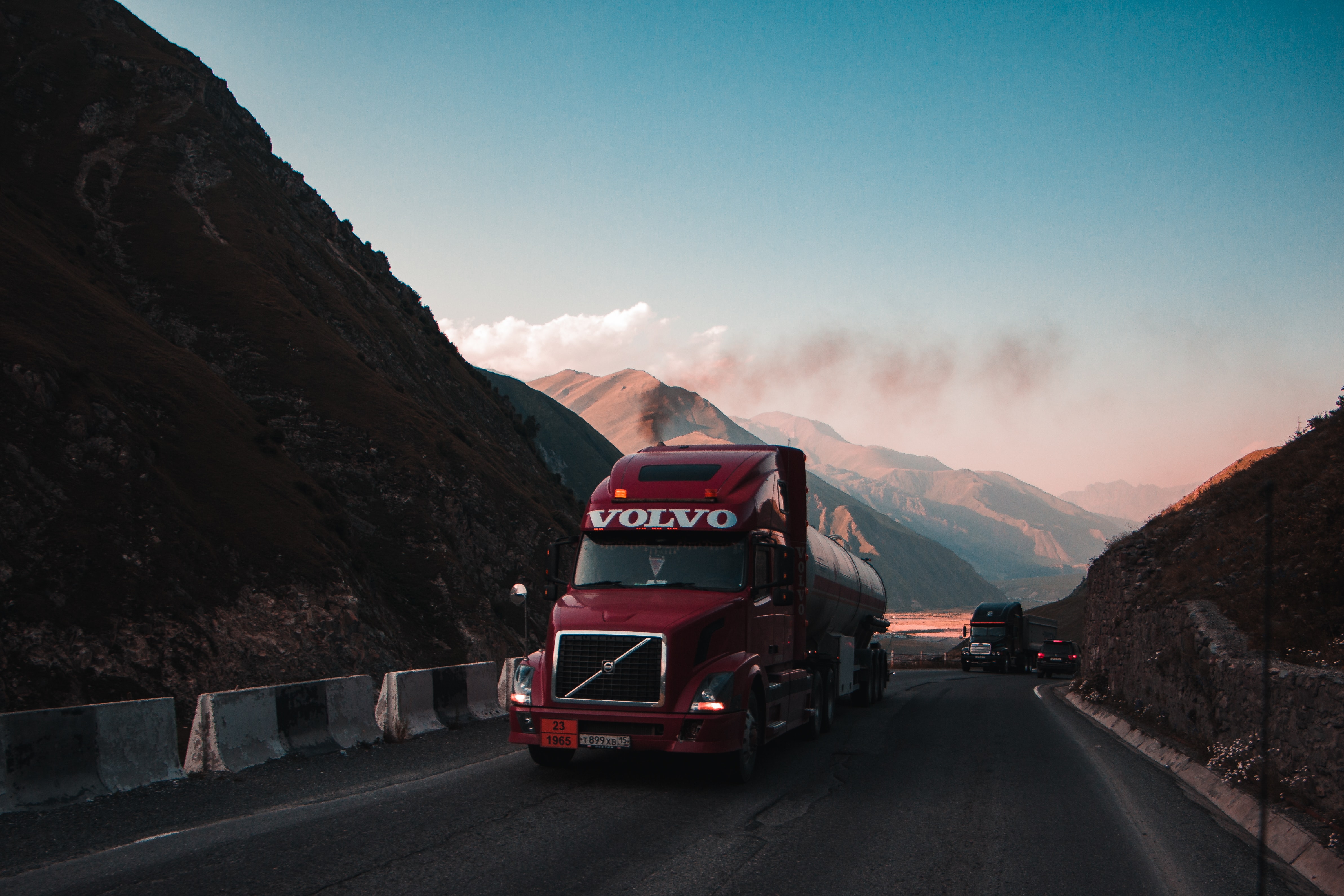 Red Volvo tanker truck on mountain pass; image by Jairph P, via Unsplash.com.