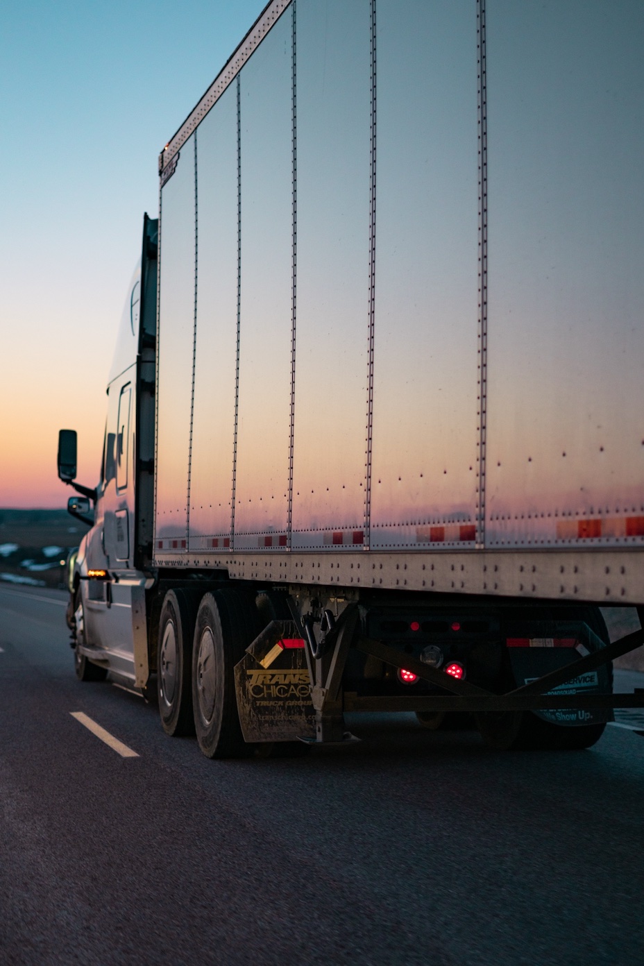 Side of truck driving into the sunset; image by Caleb Ruiter, via Unsplash.com.