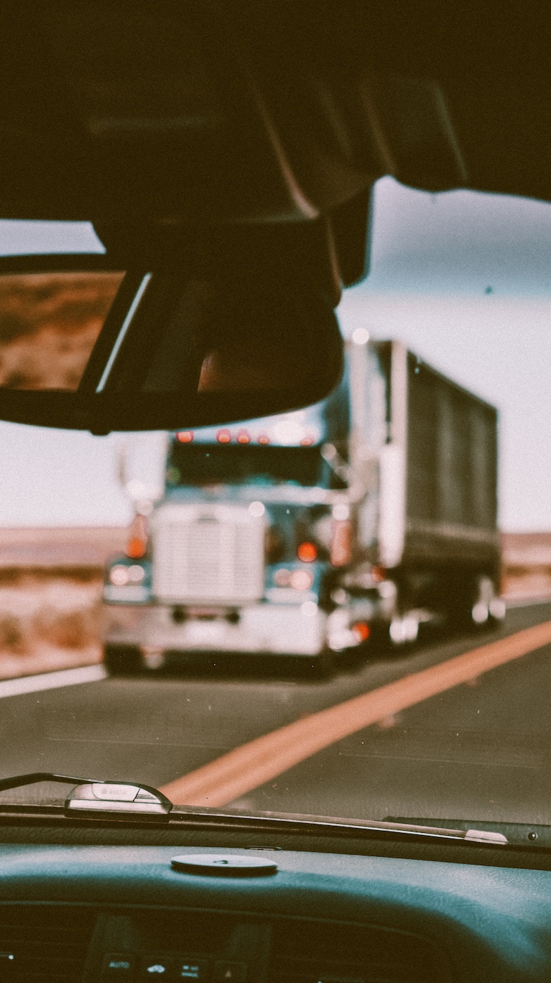 Truck in oncoming traffic, shot through car windshield; image by Ralph Ravi Kayden, via Unsplash.com.