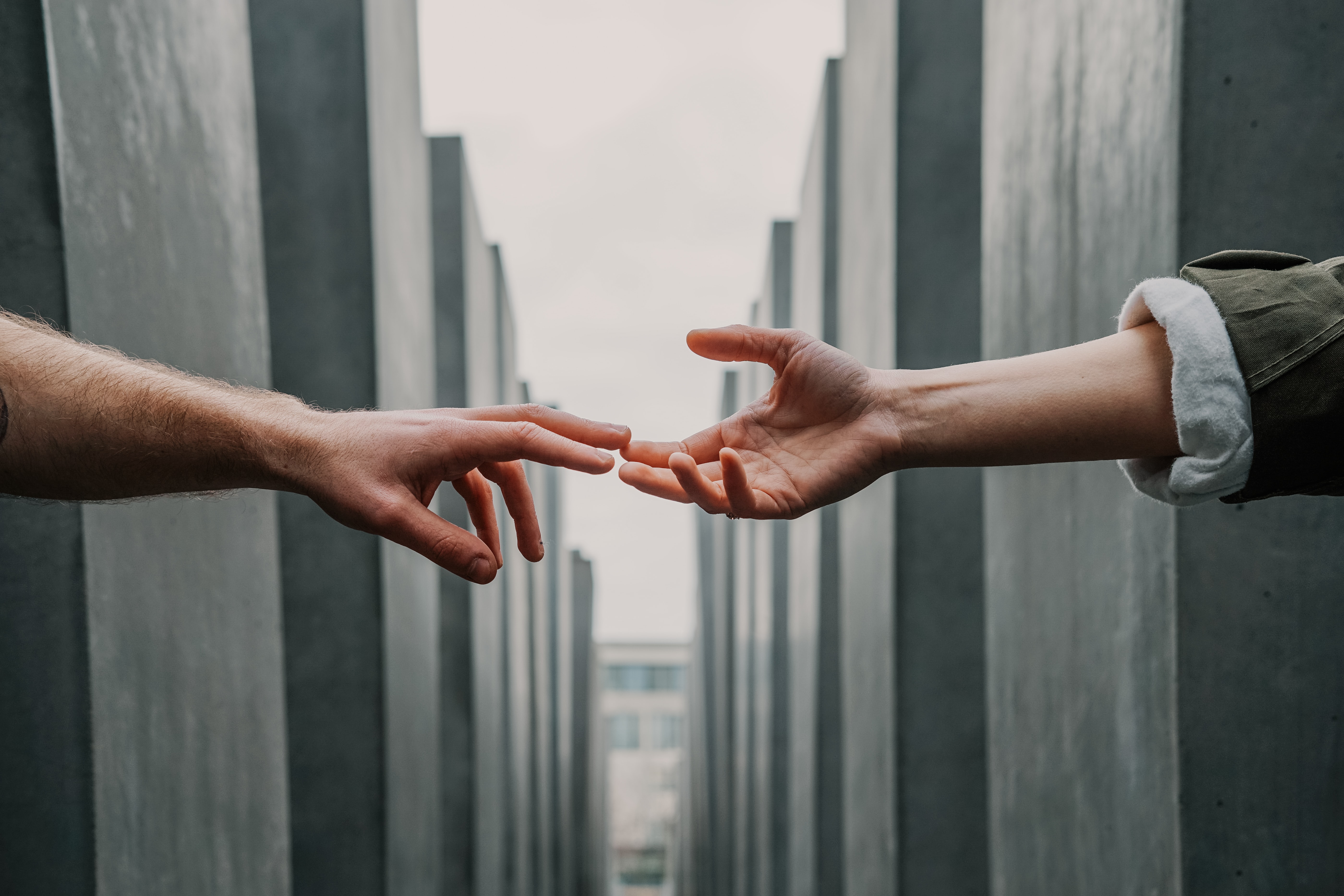 Twohands reaching for each other; image by Toa Heftiba, bia Unsplash.com.