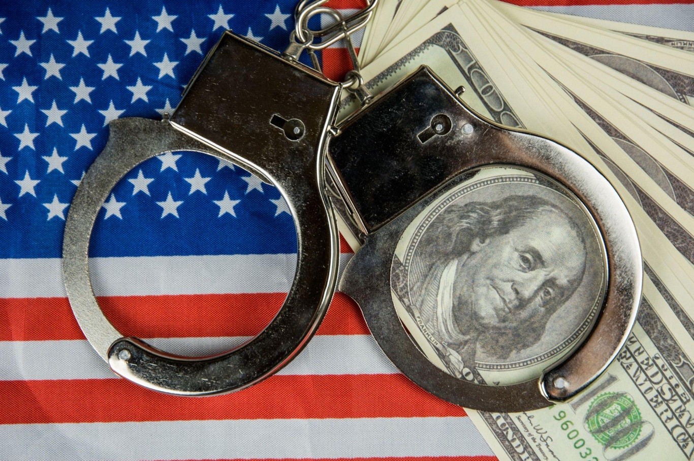 USA flag with handcuffs and a bundle of dollars; image by Bermix Studio, via Unsplash.com.