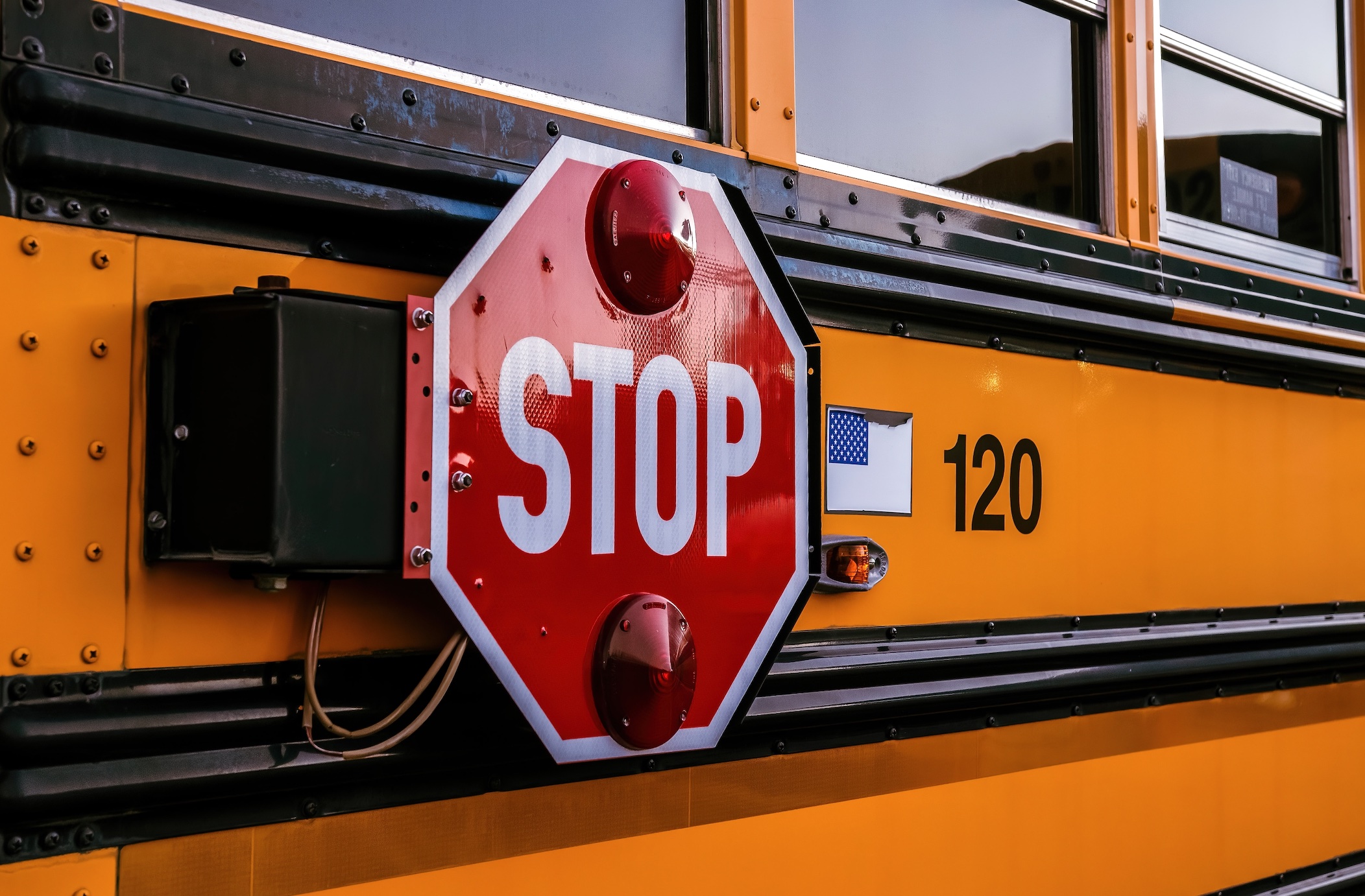 Upclose shot of stop sign on school bus; image by Robin Jonathan, via Unsplash.com.