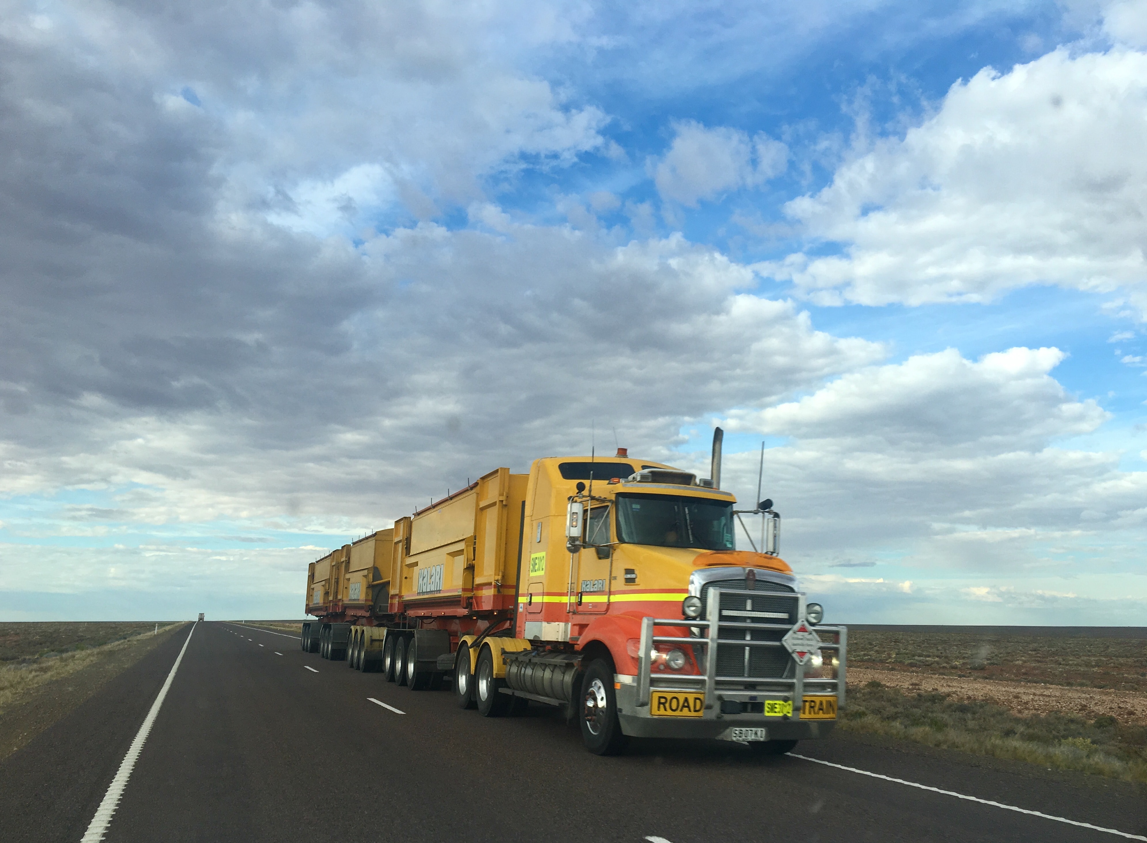 Yellow three-trailer truck on road; image by Rhys Moult, via Unsplash.com.