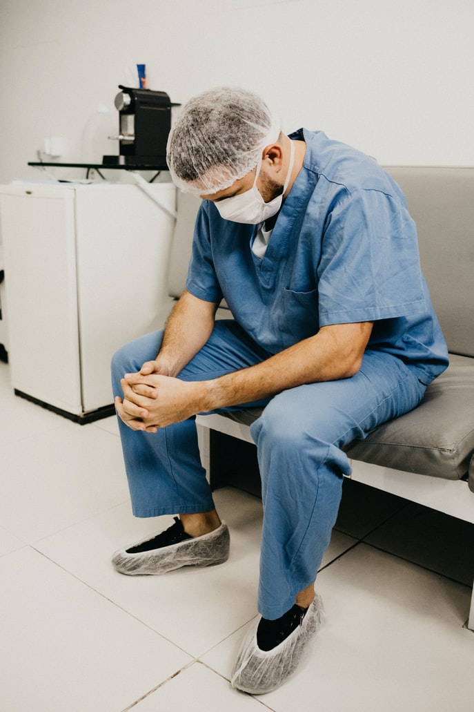 A medical worker looking exhausted, sitting at rest.