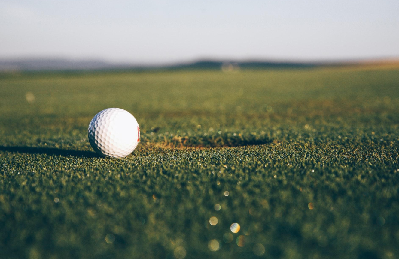 Golf ball on green near hole; image by Markus Spiske on Unsplash.com.