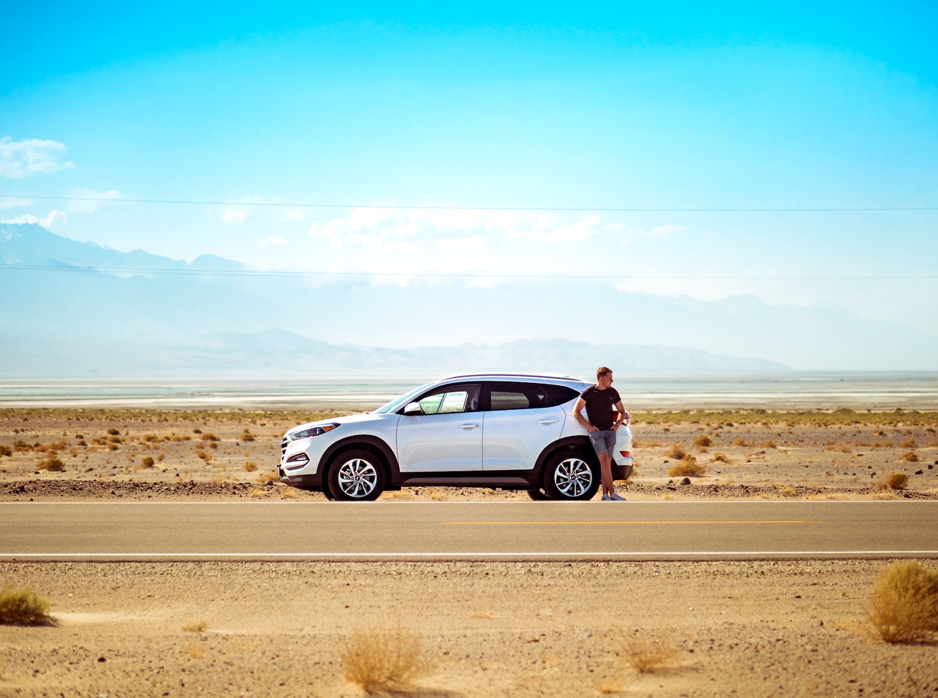 Man leaning against car on a desert road; image by Jamie Street, via Unsplash.com.