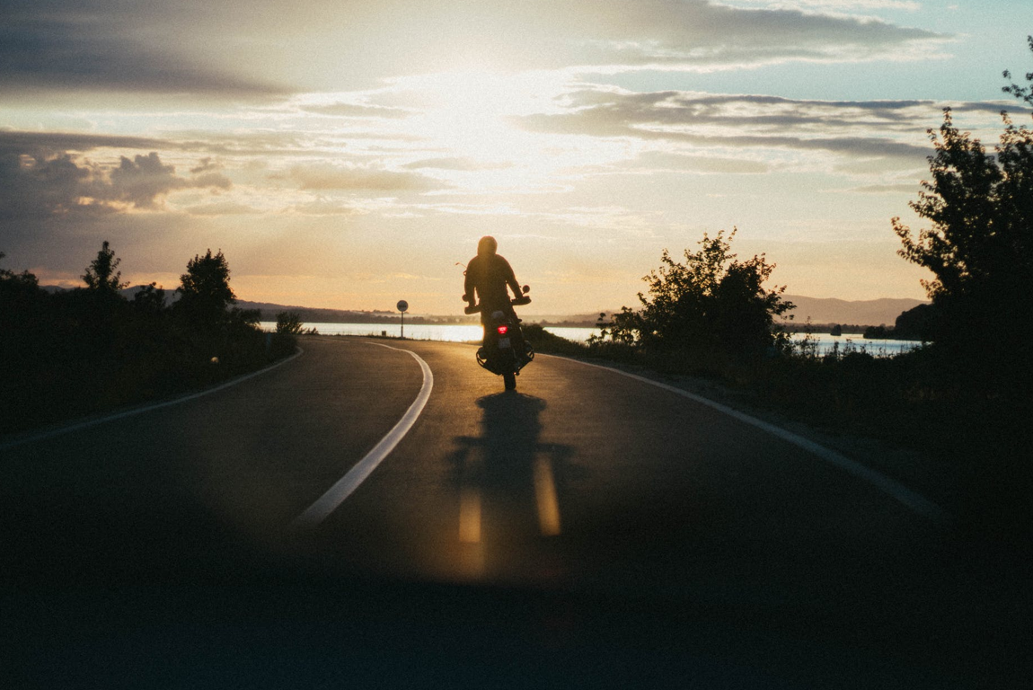 Motorcyclist riding into the sunset; image by Djordje Petrovic, via Pexels.com.