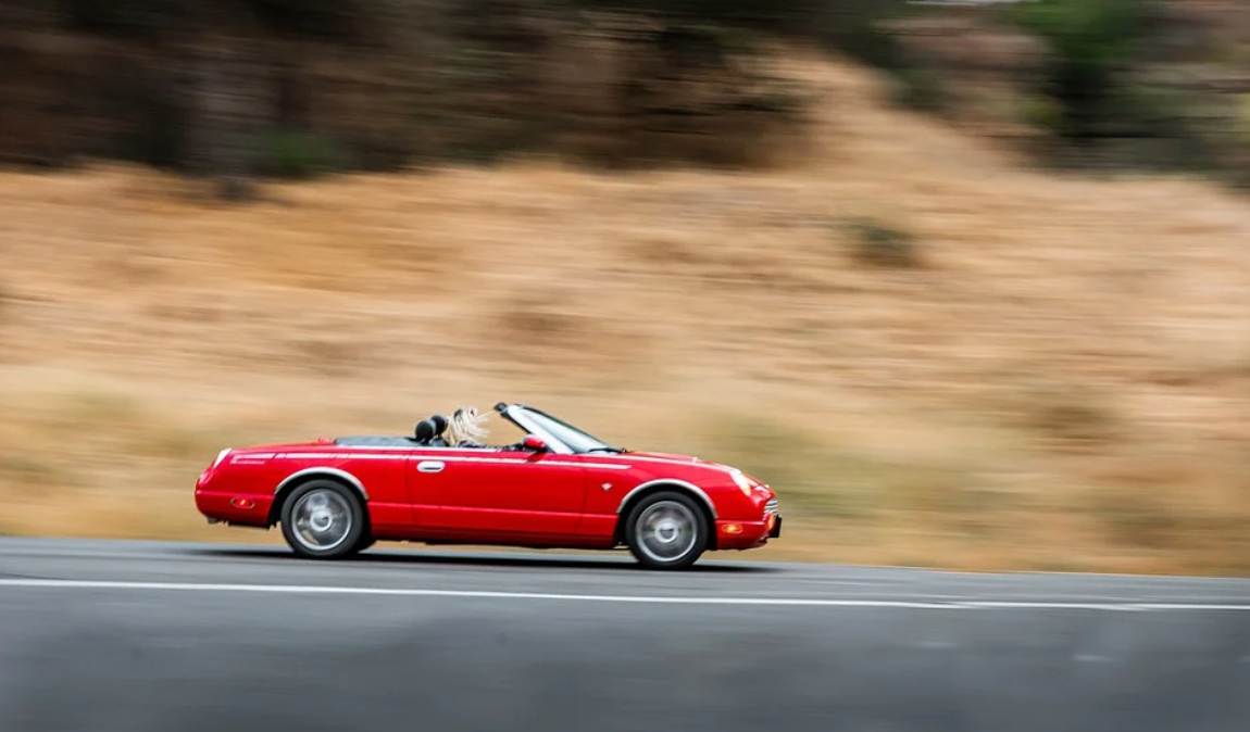 Red convertible sports car cruising at speed; image by Tyler_Clemmensen, via Pixabay.com.