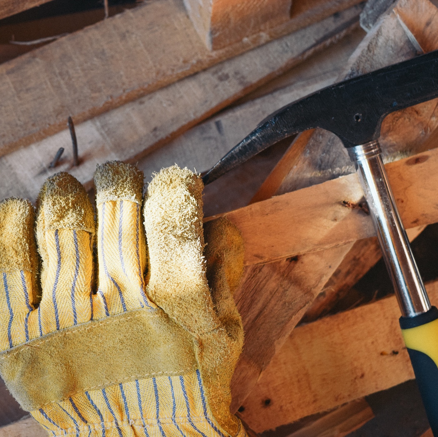 Work glove and hammer atop wood with nails poking out; image by Not Fabrik, via Unsplash.com.