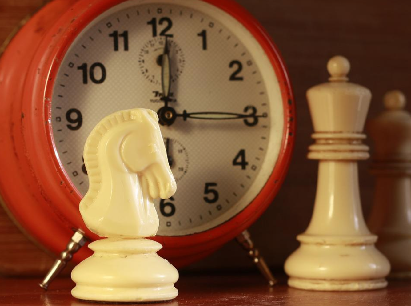 Chess pieces in front of alarm clock; image by Ikaika, via Pixabay.com.