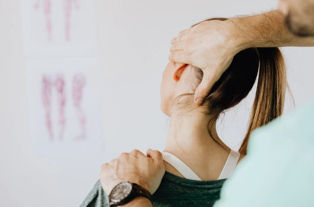 A massage therapist treating a woman's injured neck; photo by Karolina Grabowska, via Pexels.com.