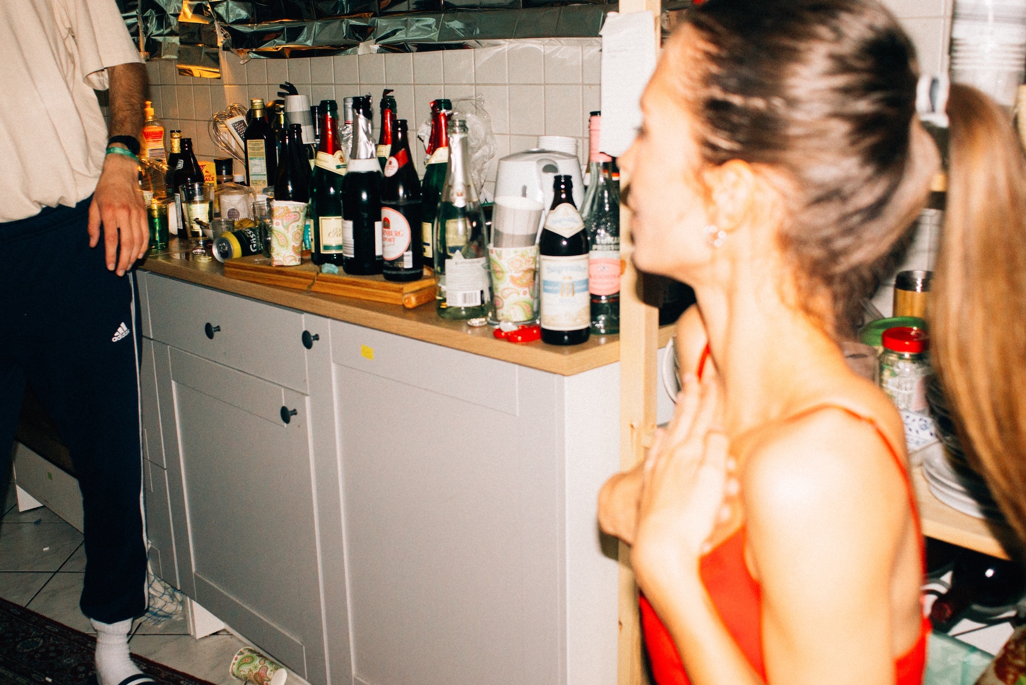 House party with many alcohol bottles on counter; image by Tobias Tullius, via Unsplash.com.