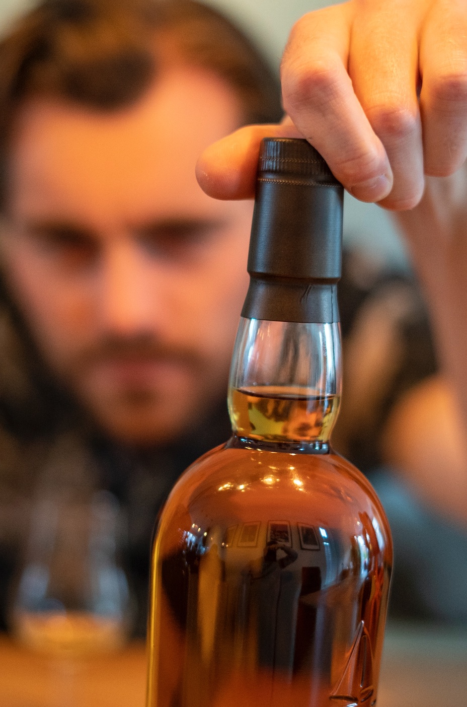 Man holding bottle of alcohol; image by Paul Einerhand, via Unsplash.com.