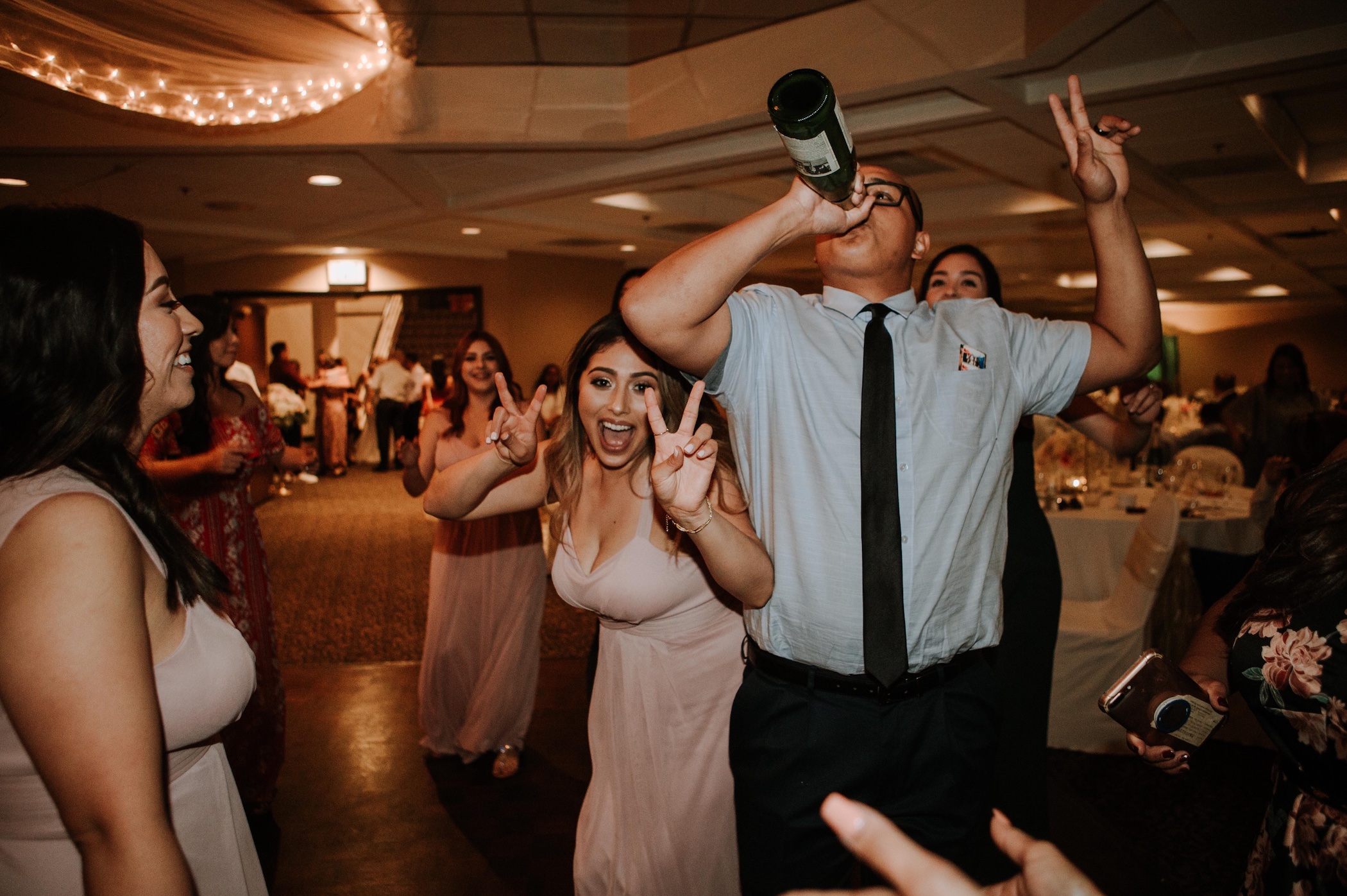 People partying, one man drinking from bottle; image by Omar Lopez, via Unsplash.com.