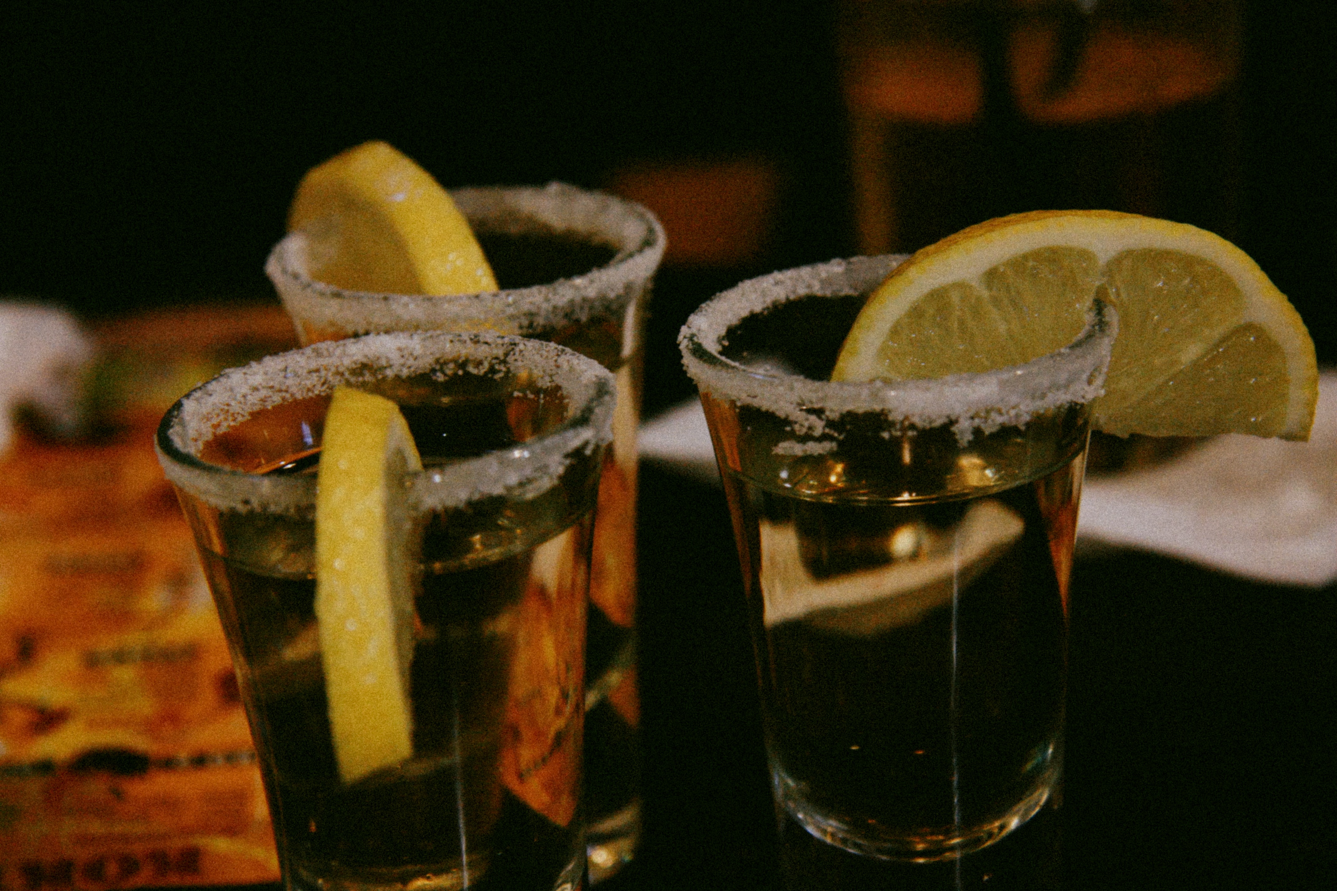 Three tequila shots on bar; image by iam os, via Unsplash.com.