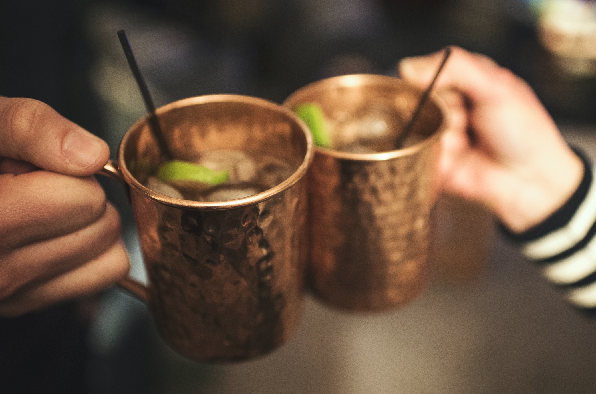 Two people toasting with Moscow Mules; image by Gary Meulemans, via Unsplash.com.