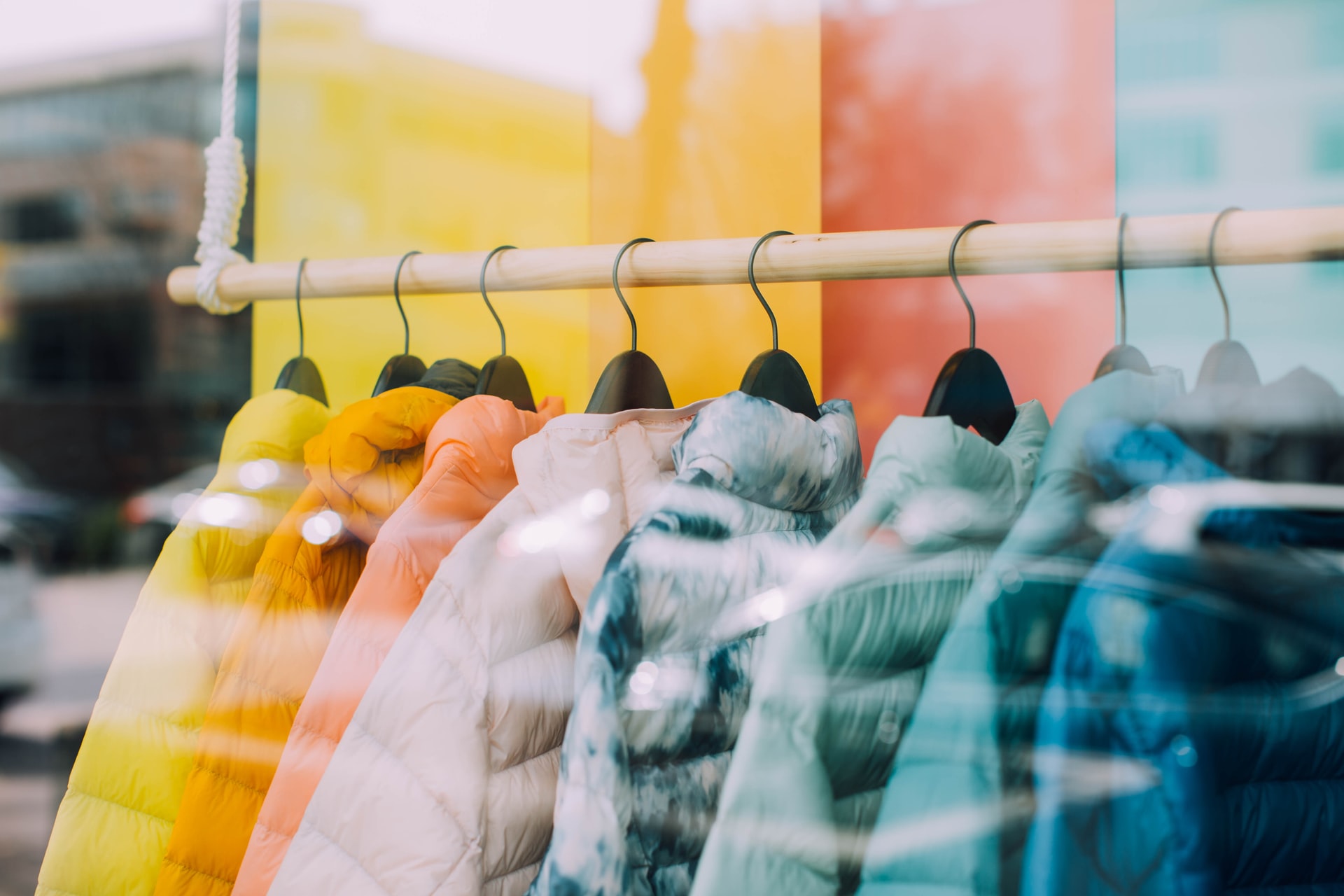 Various colored coats on a rack; image by The Nix Company, via Unsplash.com.