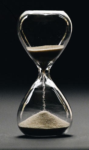An hour glass, less than half full up top, marks the loss of time.