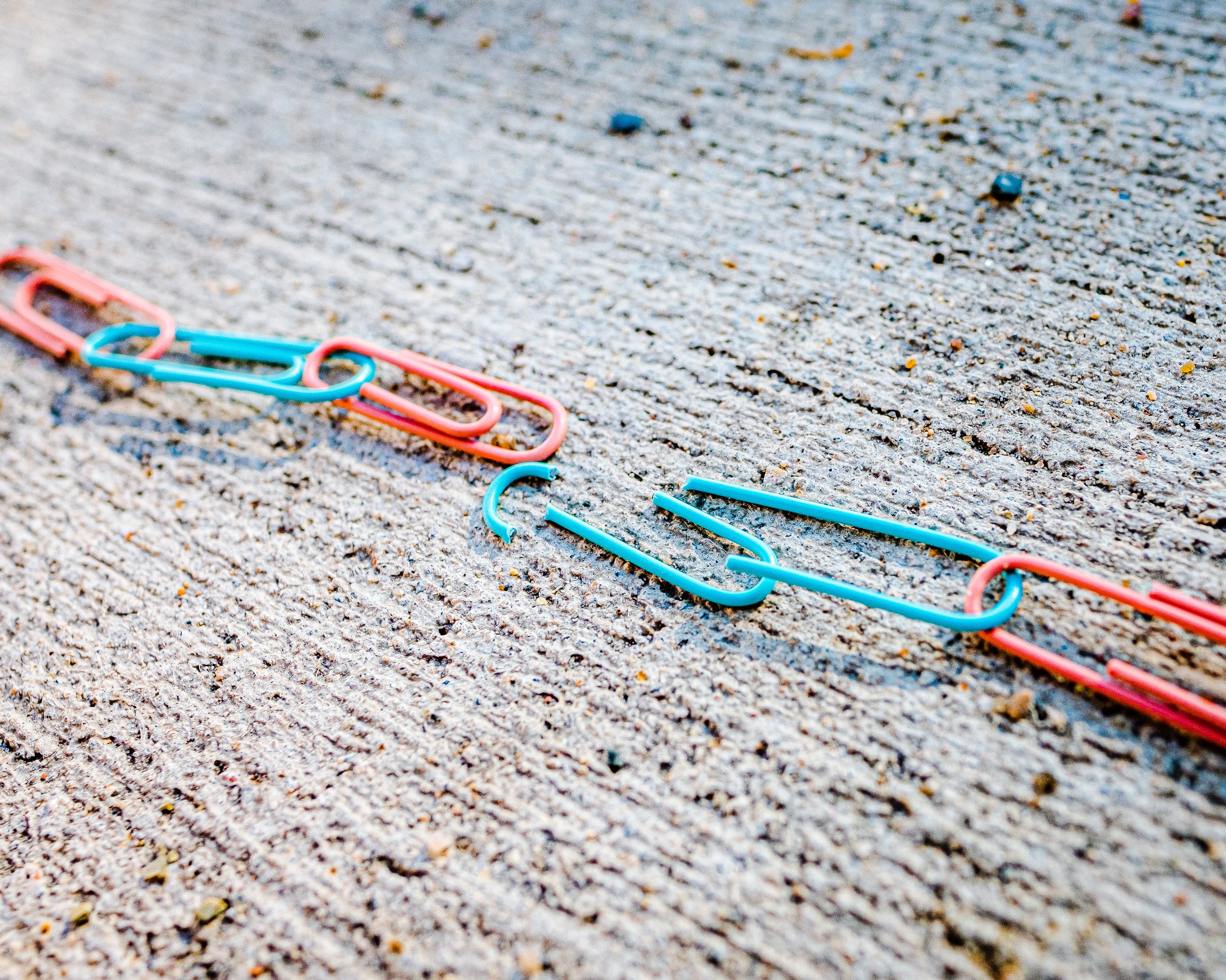 Broken chain of blue and red paperclips; image by Jackson Simmer, via Unsplash.com.