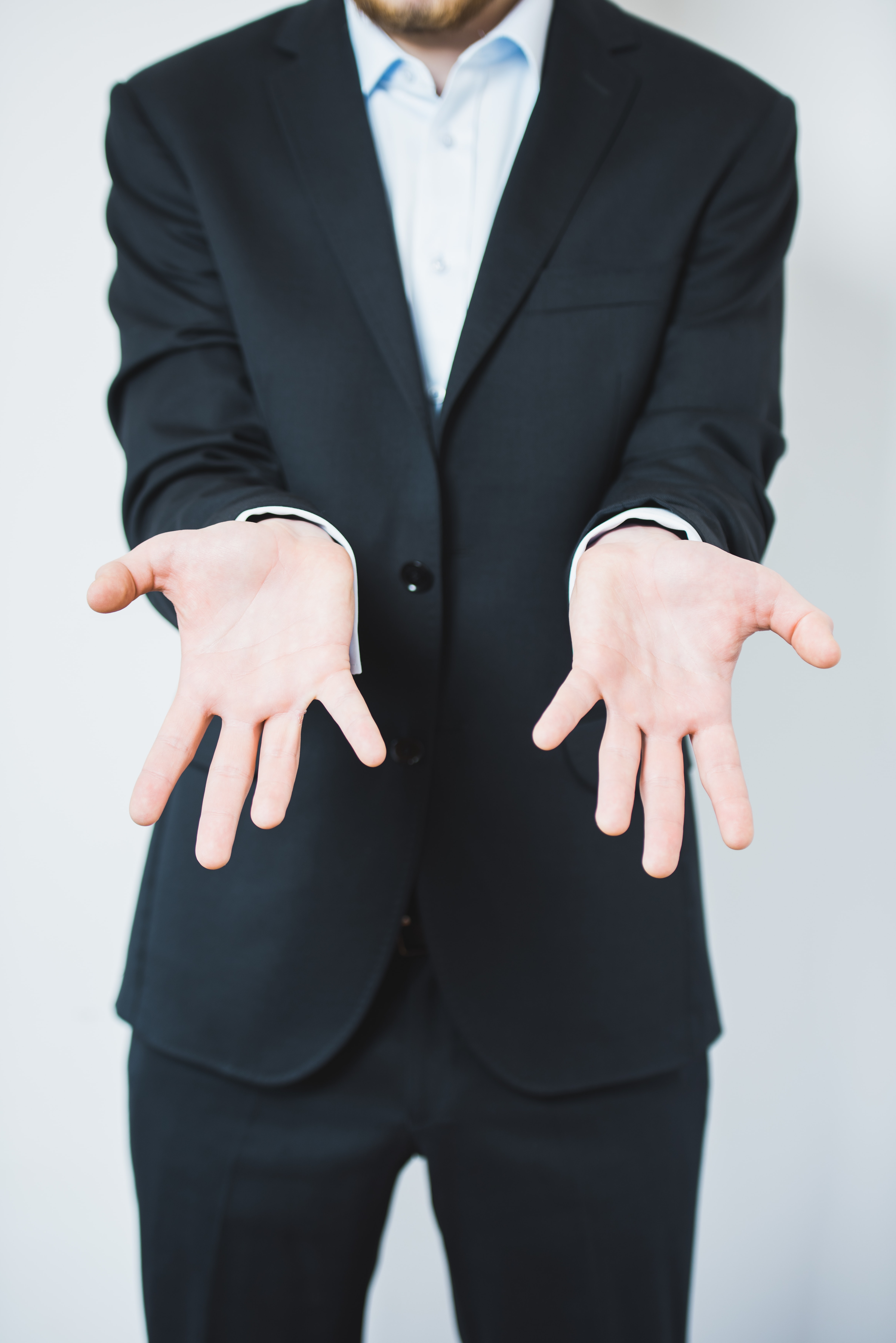 Man in suit showing empty hands; image by Jacek Dylag, via Unsplash.com.