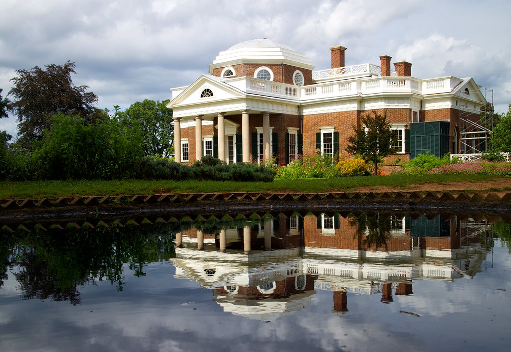 Monticello, a stately building with a rotunda and columns, reflected in water.